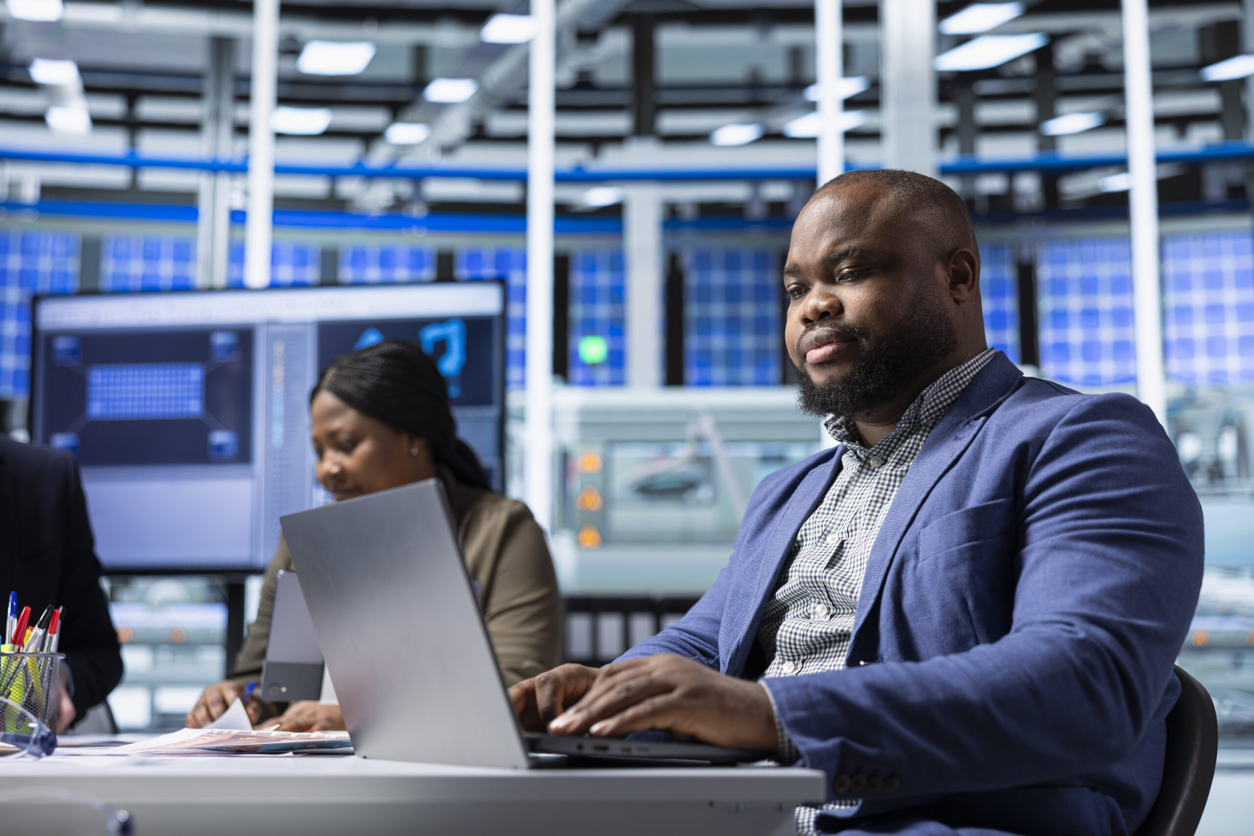 Teamworking factory colleagues researching new photovoltaics materials on notebook. Team of solar panel manufacturing plant researchers developing new solar energy systems prototypes using laptop